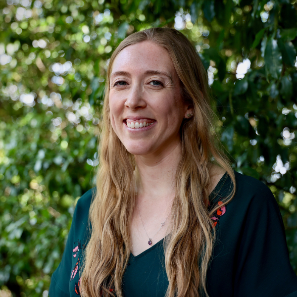 Picture of Katie Foster standing before a shaded green background